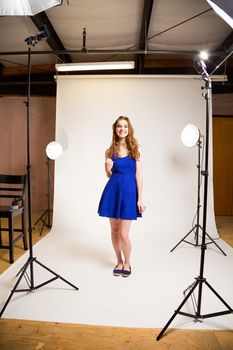 An attractive teen poses for a photo indoors in a lighting studio against a white background with a fashion style feel to the image.