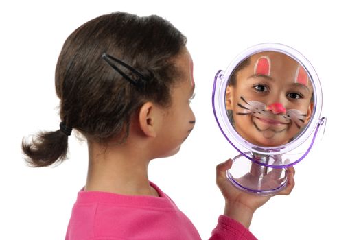 A young girl looks at herself in the mirror after her facial painting.