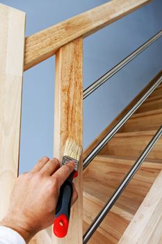 Hand applying protective oil on wooden stairs