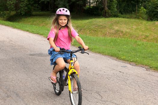  little girl in helmet learning to ride a bicycle on empty street