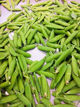Pile of green beans in a tray with white paper, at a marketplace
