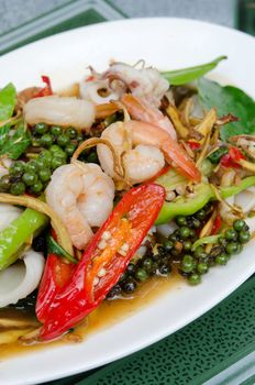  fried  seafood  with herbal vegetable on white dish , spicy seafood