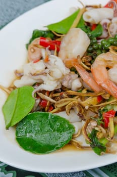 stir fried   squid  and shrimp  with mix herbal on white plate