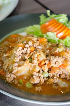 close up wide noodles with minced pork  with tomato sauce served with  fresh vegetable
