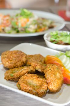 Spicy fried fish cake (Tod Mun Pla) served with cucumber and tomato on dish , thai food