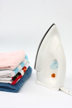 Pile of colorful clothes and electric iron on white background