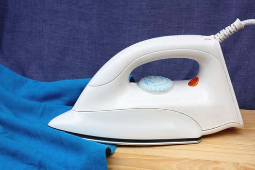 Electric iron and shirt, on white and blue background