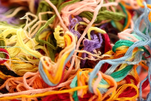 a tangle of colored threads for embroidery and needle