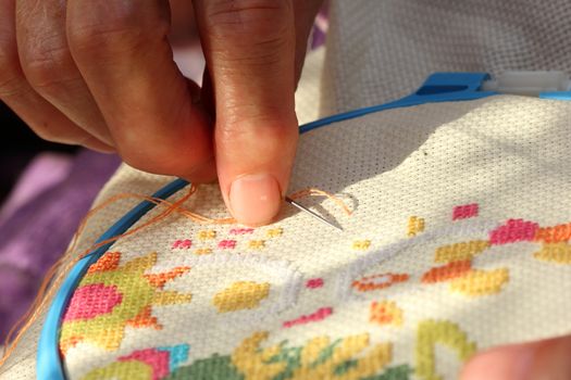 Hands of an old woman busy embroidering