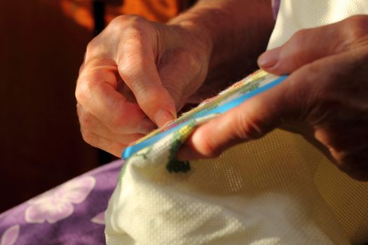 Hands of an old woman busy embroidering