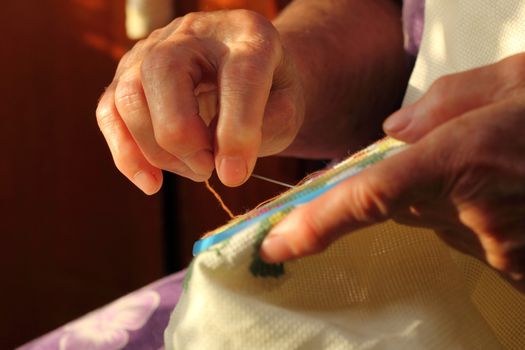 Hands of an old woman busy embroidering