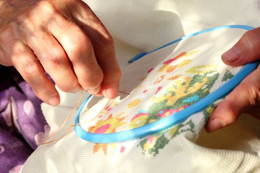 Hands of an old woman busy embroidering