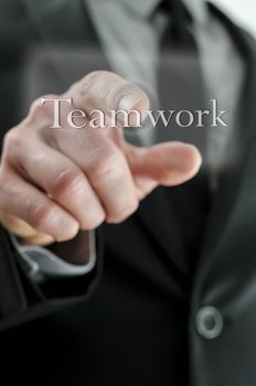 Closeup of businessman hand pressing Teamwork icon on a virtual screen.