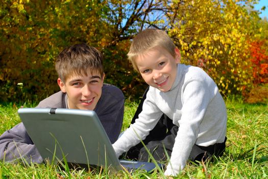 teenager and kid with notebook on the meadow