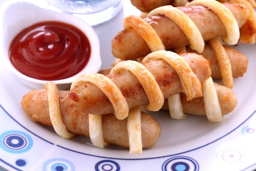 Fresh baked twisted pastry around chicken sausages with ketchup.