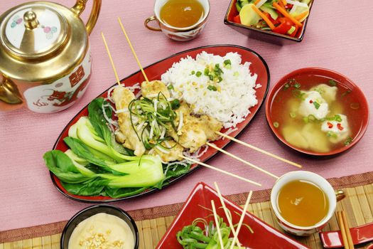 Asian chicken skewers with short soup and vegetables.