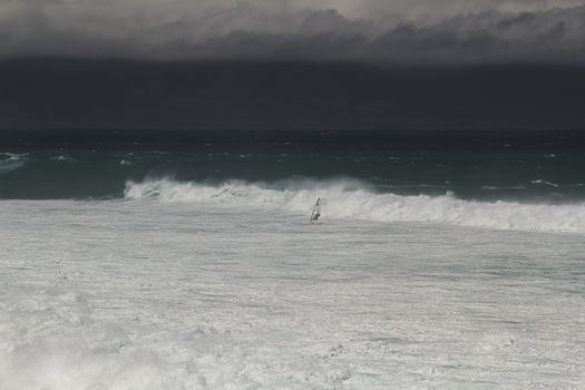 Windsurfer in the distance surfing away from a storm surge