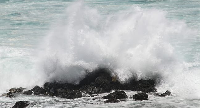 close-up of a wave crashing over rocks