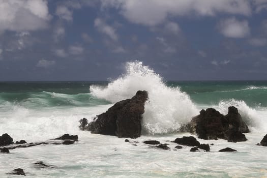 volcanic rock formation being pounded by wave