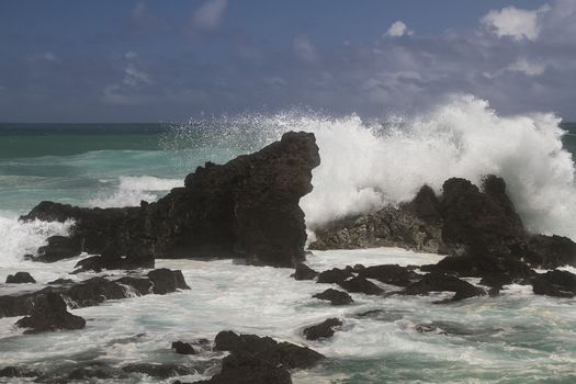volcanic rock formation being pounded by wave