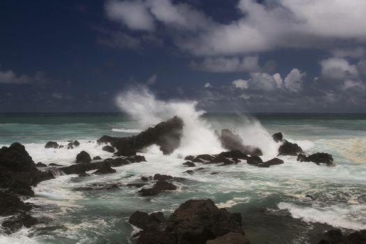 volcanic rock formation being pounded by wave