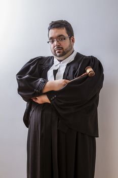 Man in canadian lawyer toga holding a hammer against a white background