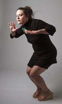 Woman wearing a black dress with wispy flowing hair, with scared expression