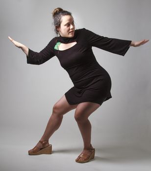 Woman wearing a black dress with wispy flowing hair in the middle of a dance pose
