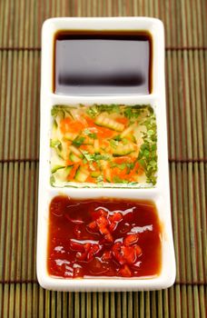 Asian dipping sauces consisting of chillie sauce, soy sauce and cucumber and parsley sauce.