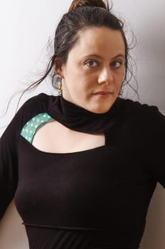 Woman wearing a black dress with wispy flowing hair against a wall