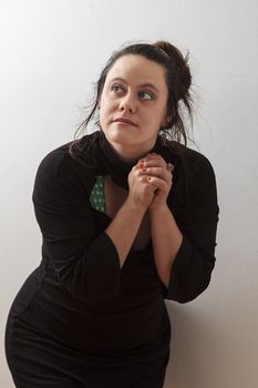 Woman wearing a black dress with wispy flowing hair holding her hand in praying positiong