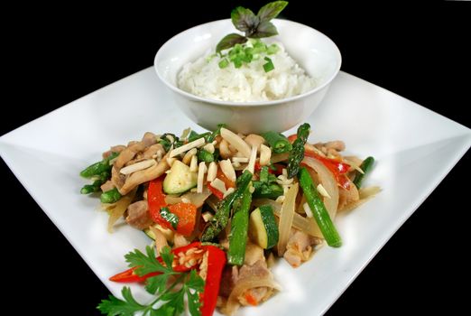 Delicious chicken stirfry and rice with almonds, asparagus, beans and peppers.