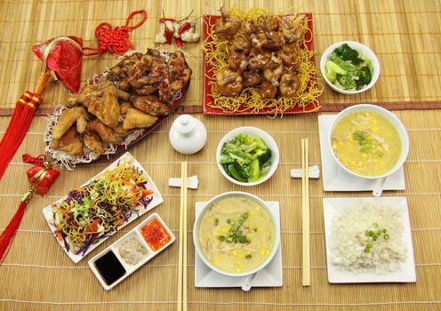 Table setting of  asian chicken pieces with chicken and corn soup, rice and asian vegetables.