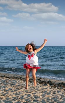 happy little girl jumping on the beach
