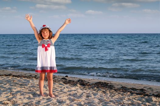 happy little girl with hands up on beach