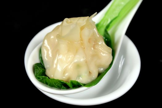 Steamed dim sum with bok choy on spoon.