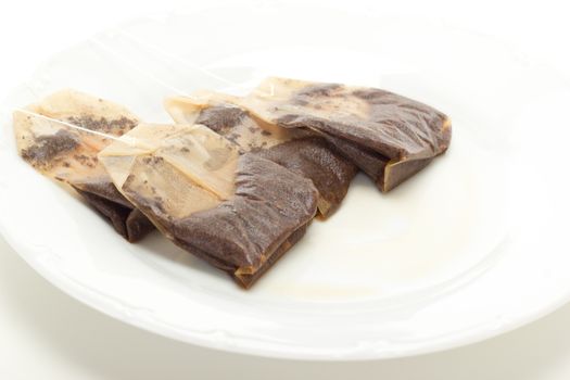Some removed tea bags on white dish