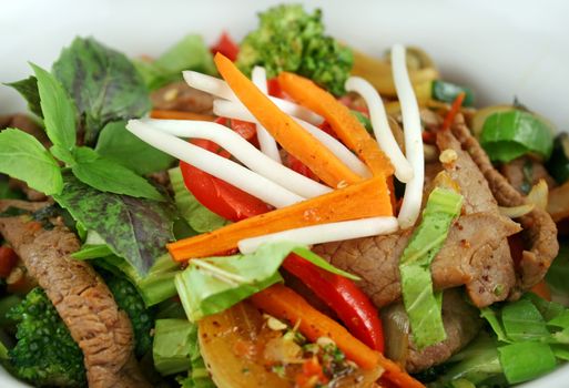 Stirfry beef and vegtables with a purple green basil garnish.