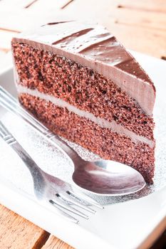 Piece of chocolate cake serving with spoon and fork