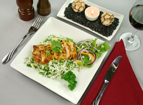 Table setting of chicken tikka on a bed of lemon coriander rice with salad.