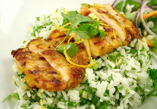 Sliced chicken tikka on a bed of lemon coriander rice with salad.