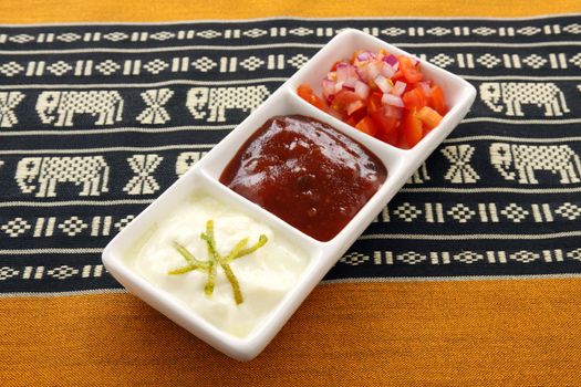 Indian condiments consisting of yoghurt and lime, chutney and tomato and onion.