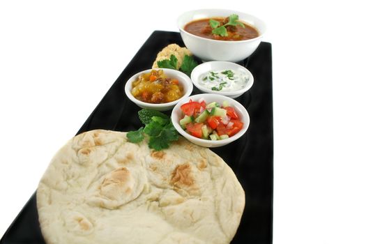 Indian feast of vindaloo curry, naan bread, mango chutney, banana and coconut, tomato and cucumber.