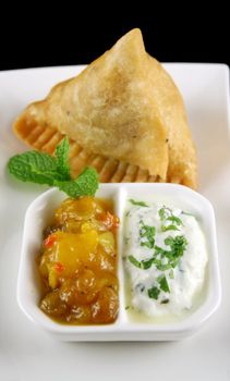 Indian samosa with mango chutney and herb yogurt.