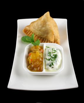 Indian samosa with mango chutney and herb yogurt.