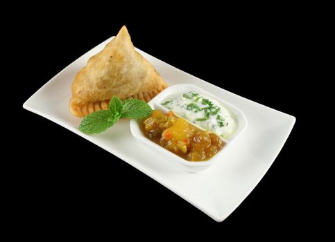 Indian samosa with mango chutney and herb yogurt.