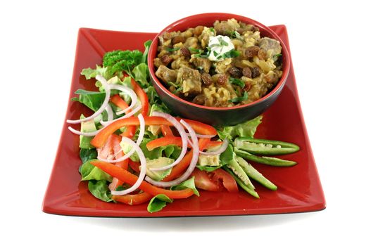 Indian lamb biryani with sultanas and yoghurt and a side salad.