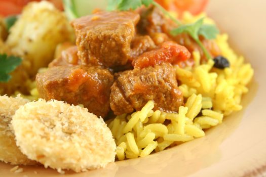 Beef vindaloo curry on tumeric rice with a side salad.