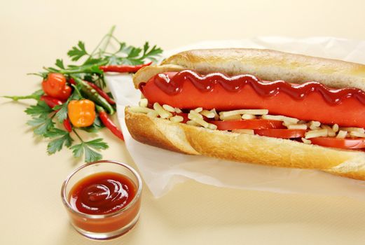 Freshly prepared hot dog with ketchup tomato cheese and fresh chillies.