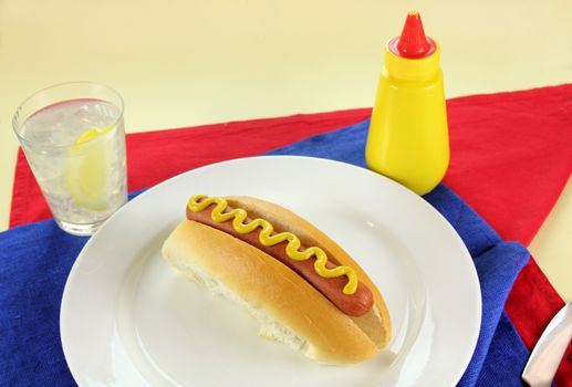 Amrerican hot dog with mustard on red, white and blue napkins with copy space.